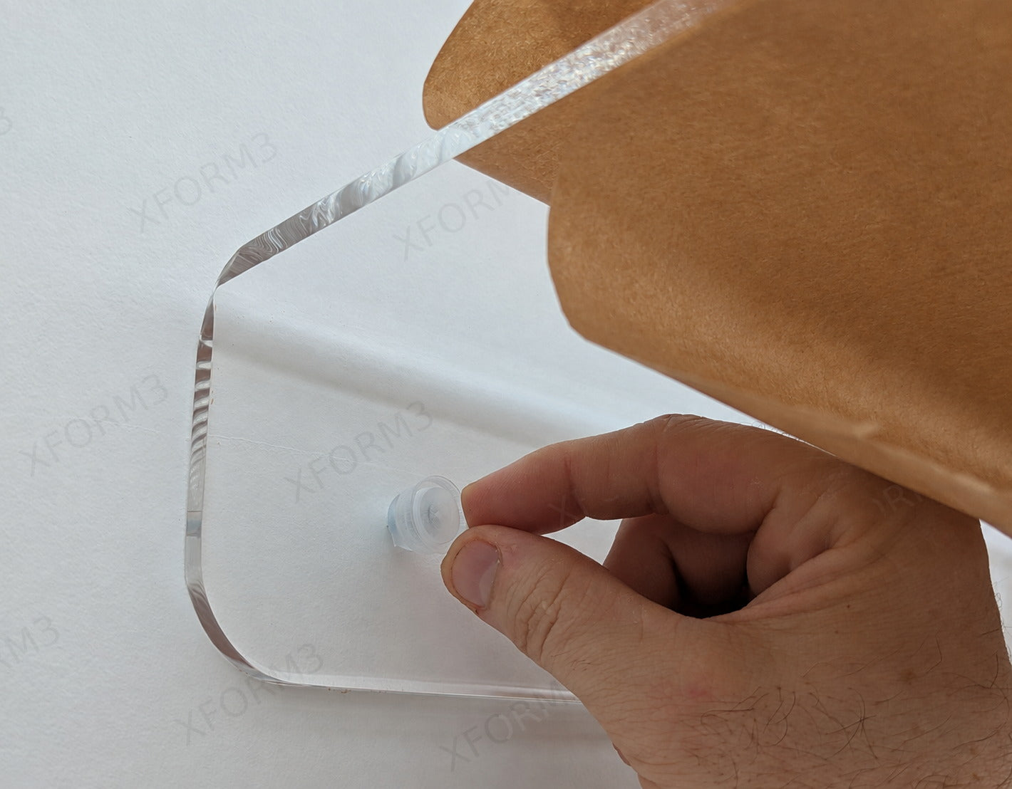 Hand pressing a clear acrylic cover cap over an installed shelf screw
